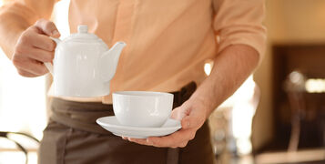 Waiter,Holding,Teapot,And,Cup,Close,Up