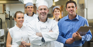 Head,Chef,Posing,With,The,Team,Behind,Him,In,A