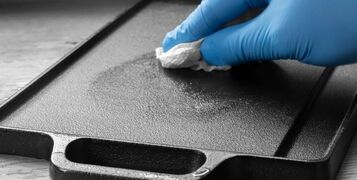 Person,Seasoning,A,Cast,Iron,Plate,With,Olive,Oil,Using